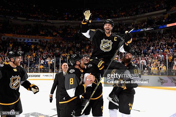 John Scott of the Arizona Coyotes is held up by teammates Mark Giordano of the Calgary Flames and Brent Burns and Joe Pavelski of the San Jose Sharks...