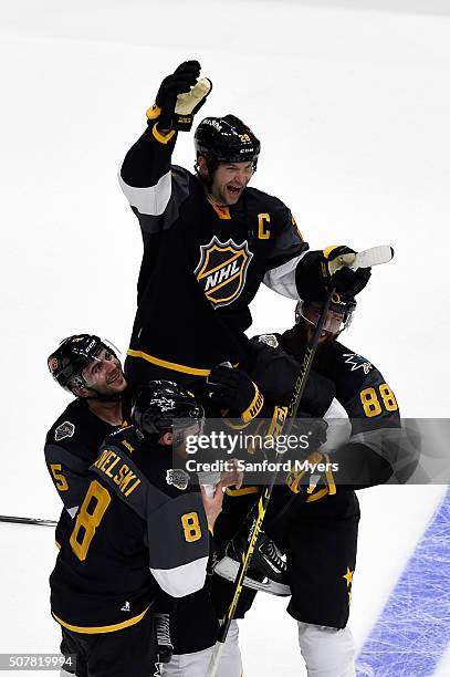 Joe Pavelski of the San Jose Sharks, Mark Giordano of the Calgary Flames, and Brent Burns of the San Jose Sharks hoist John Scott of the Arizona...