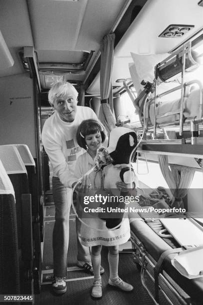 English DJ and broadcaster Jimmy Savile posed with a young girl inside the Jumbulance ambulance in London on 29th May 1980.