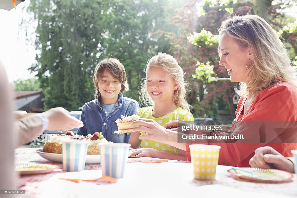 Mother serving birthday cake to family at birthday party