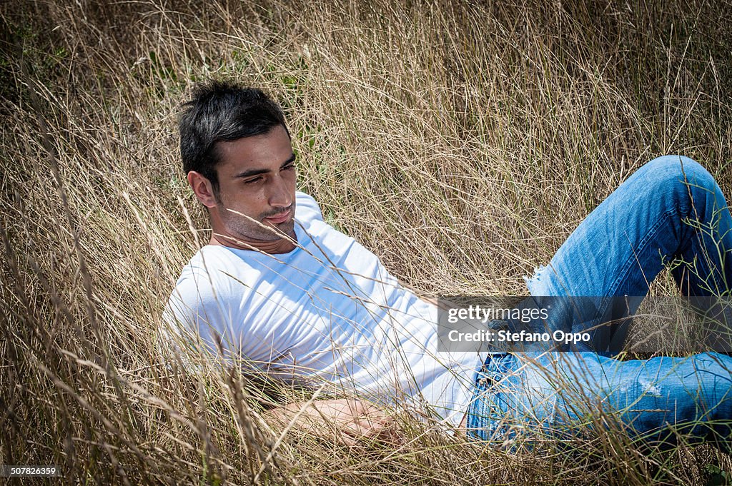 Portrait of young man reclining in long grass