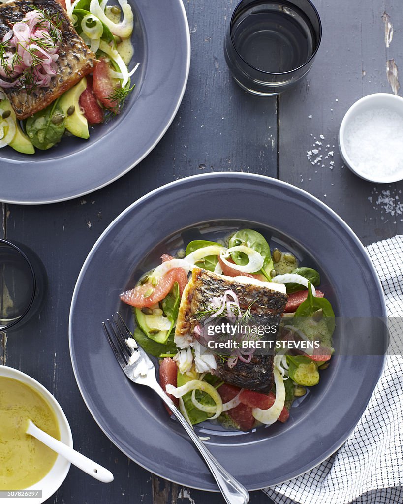 Plate of barramundi fish with vegetables and a herb garnish