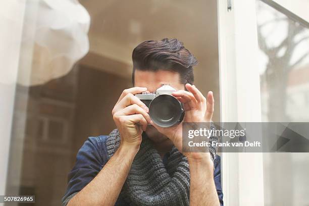 portrait of young man photographing with slr camera - spiegelreflexkamera stock-fotos und bilder