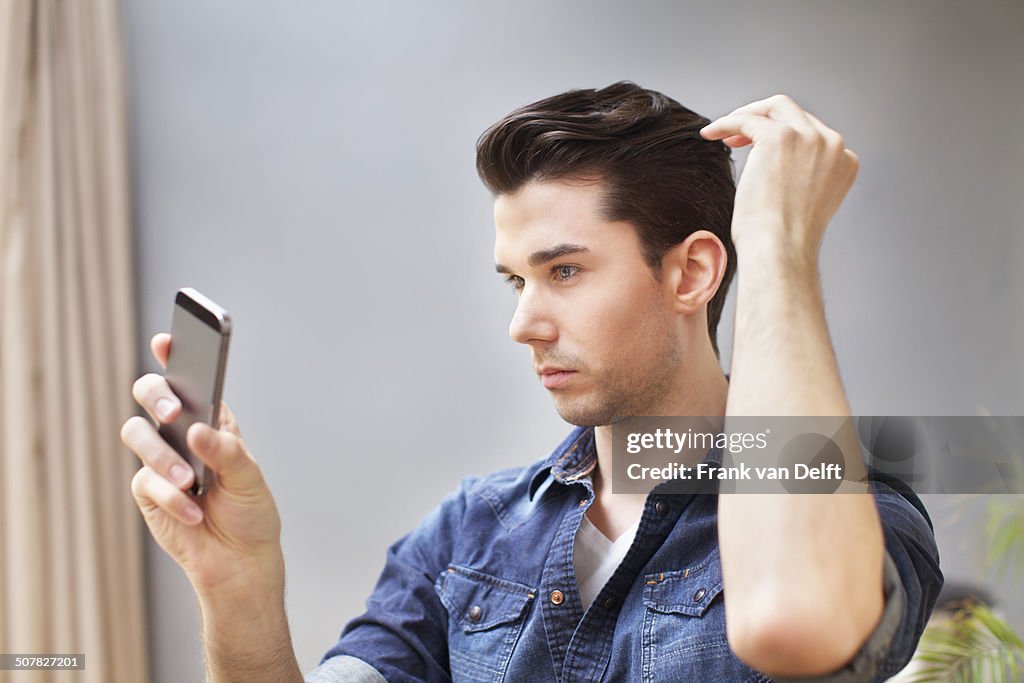 Young man taking selfie on smartphone in living room