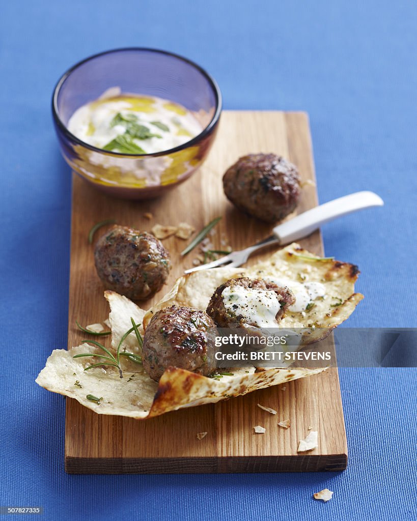Lebanese meatballs on chopping board with dipping sauce