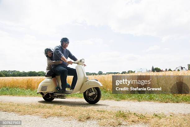 mature man and daughter riding motor scooter along dirt track - riding vespa stock pictures, royalty-free photos & images