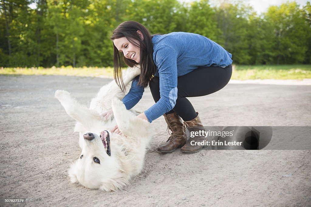 Young woman petting golden retriever on roadside