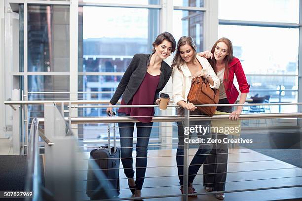 three businesswomen watching from balcony in conference centre - nosy woman stock pictures, royalty-free photos & images