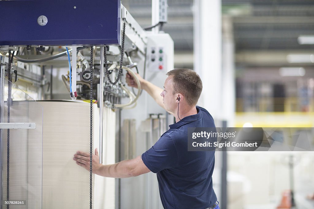 Worker using machine in paper packaging factory