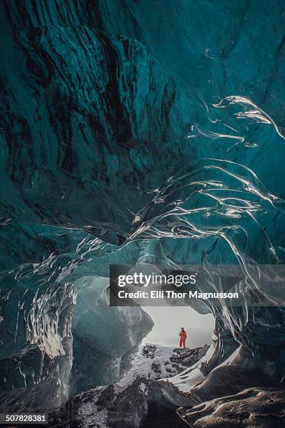 man standing at ice cave entrance, vatnajokull glacier, vatnajokull national park, iceland - iceland cave stock pictures, royalty-free photos & images