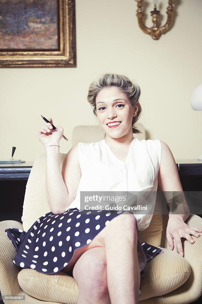 Portrait of young woman in armchair wearing vintage clothes