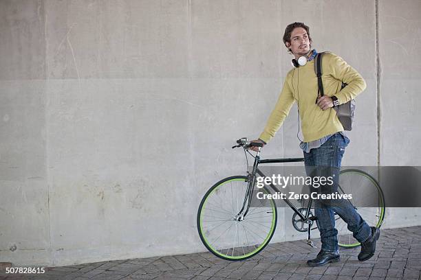 mid adult man pushing bicycle through city underpass - paso inferior fotografías e imágenes de stock