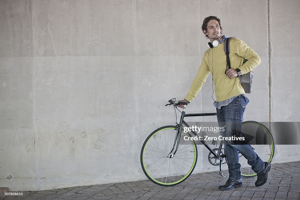 Mid adult man pushing bicycle through city underpass