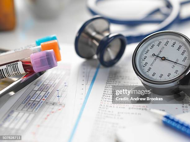 doctors desk with patients test results, samples, stethoscope and blood pressure gauge - gereedschap stockfoto's en -beelden