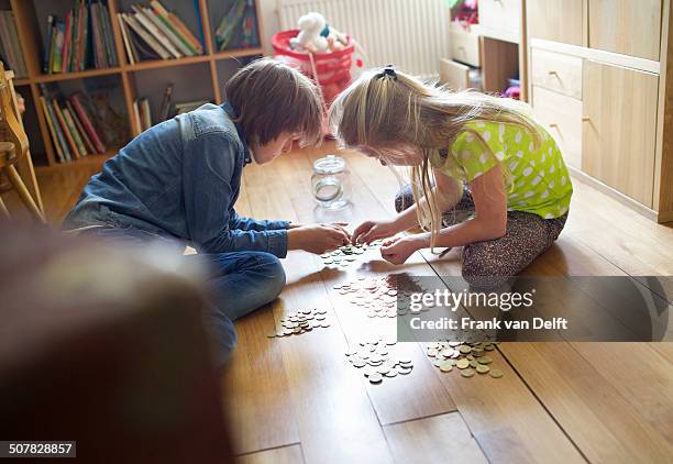 brother and sister counting coins from savings jar - taschengeld kind stock-fotos und bilder