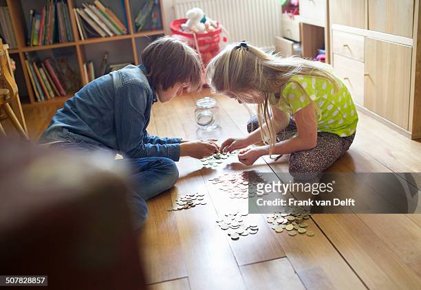 brother and sister counting coins from savings jar - kids saving money stock pictures, royalty-free photos & images