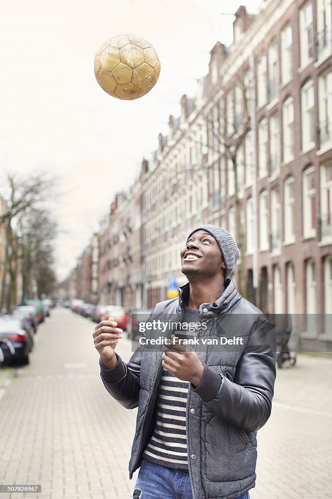 Young man on street throwing soccer ball, Amsterdam, Netherlands