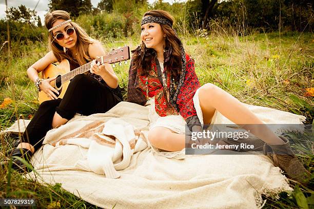 hippy girls on blanket in field, playing guitar - 1970's long hair stock-fotos und bilder