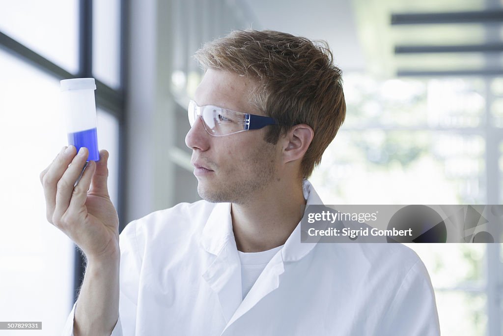 Male scientist analyzing sample in plastic bottle in lab