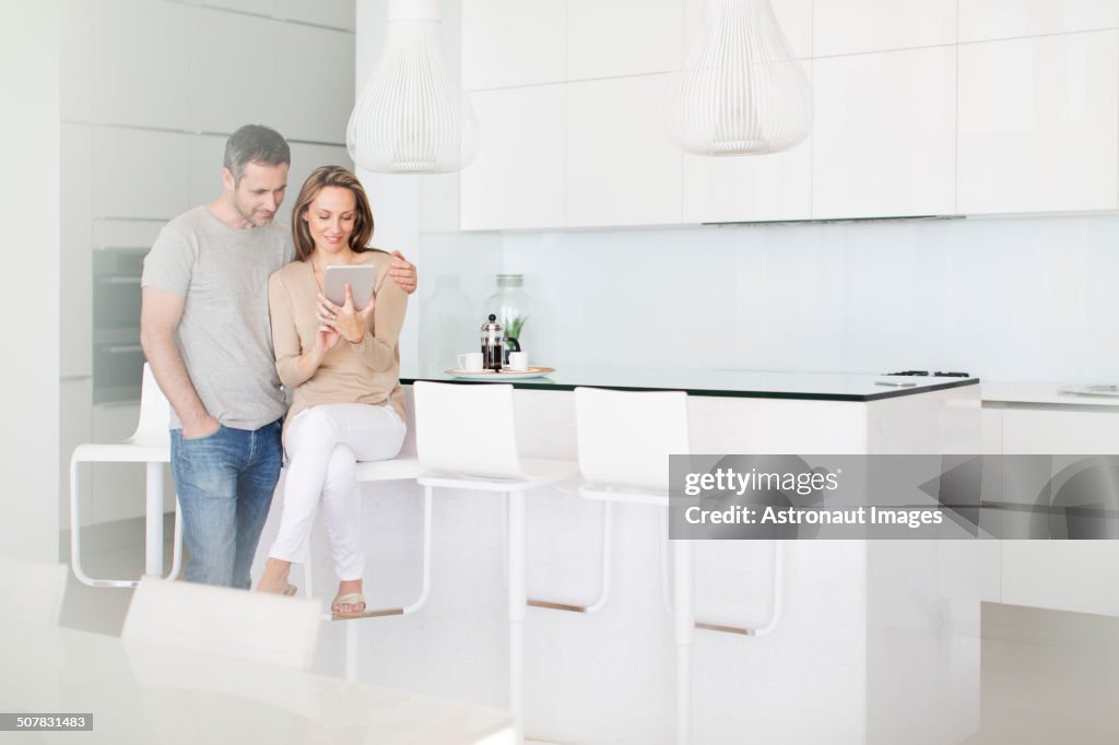 Couple using digital tablet in kitchen