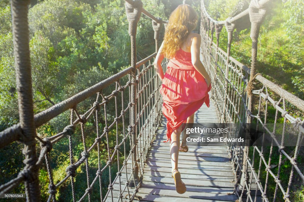 Frau, die auf einer hölzernen Seilbrücke spazieren geht