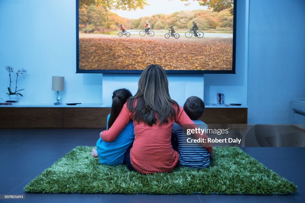 Mother and children watching television in living room