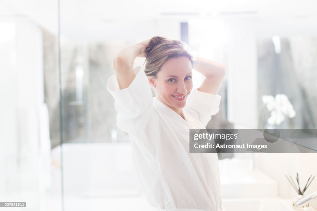 Woman putting up her hair in bathroom