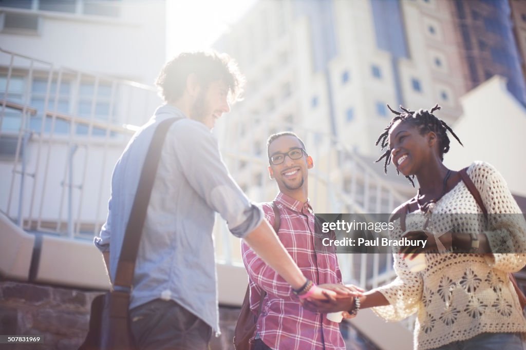 People shaking hands on city street