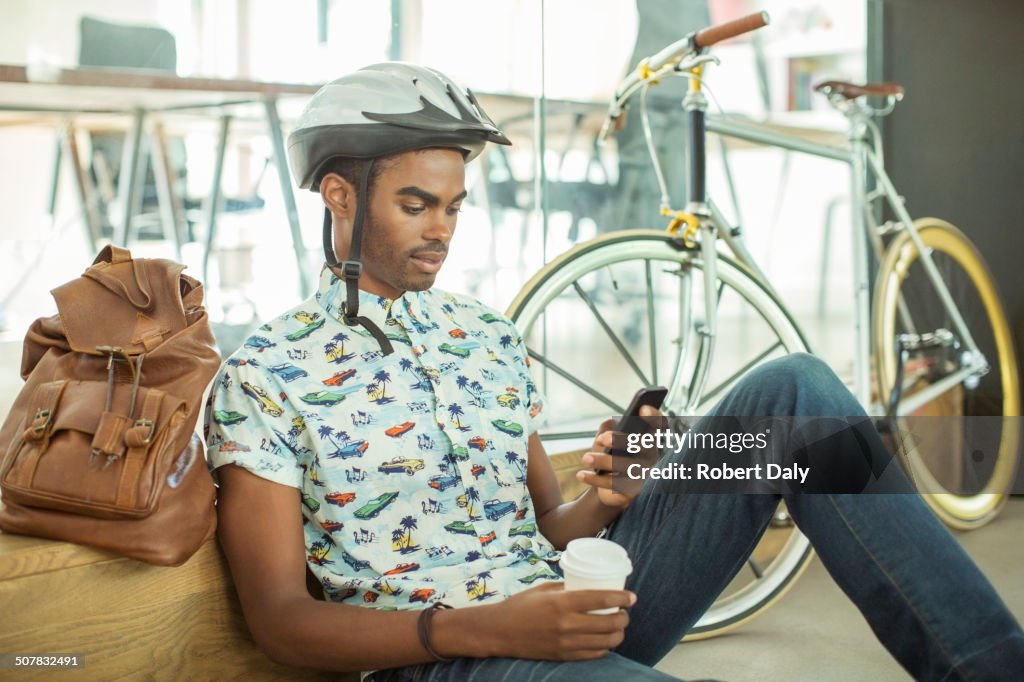 Man in bicycle helmet using cell phone in office