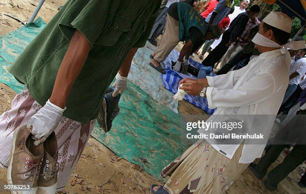 Villagers carry the shoes of the unclaimed bodies of those killed in Wednesday's deadly clash, during a mass funeral ceremony on April 29, 2004 in...