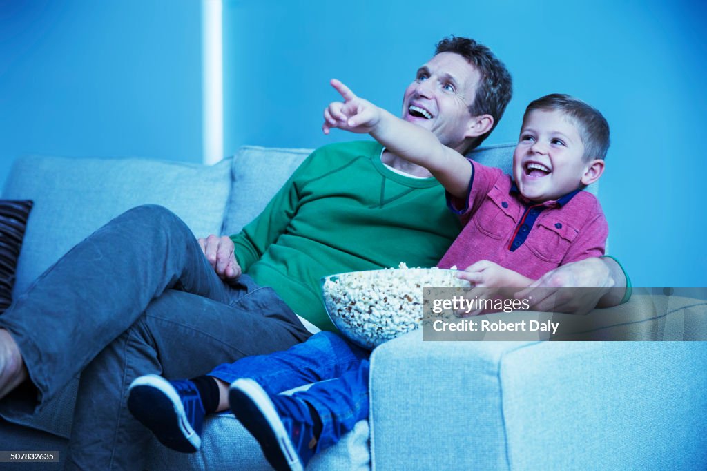 Père et fils regardant la télévision dans le salon