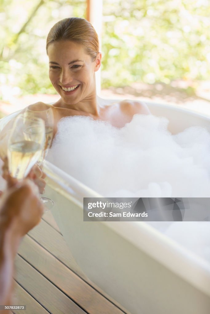 Couple toasting each other in bubble baths