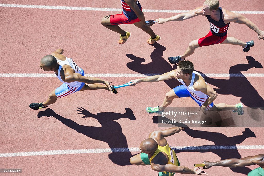 Relay runners passing batons on track