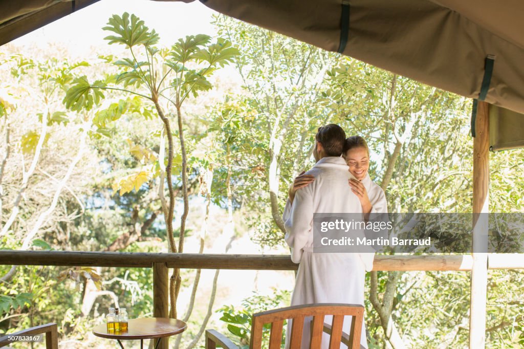 Couple in bathrobes hugging on balcony