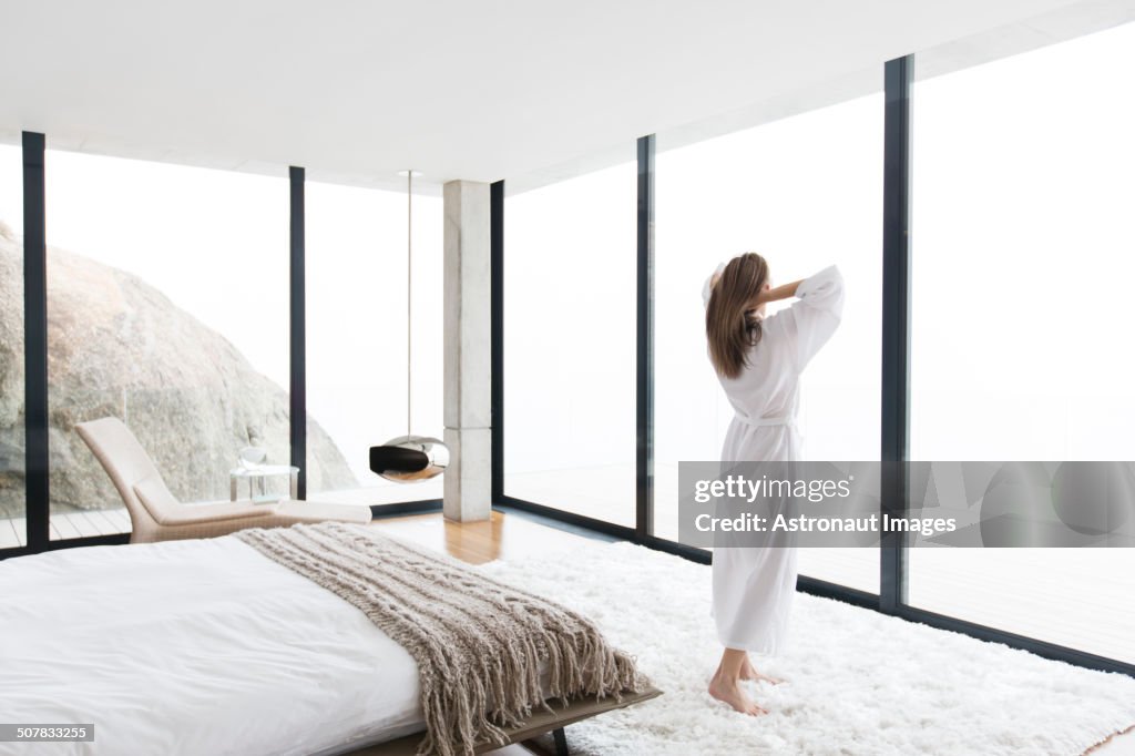 Woman wearing bathrobe in modern bedroom