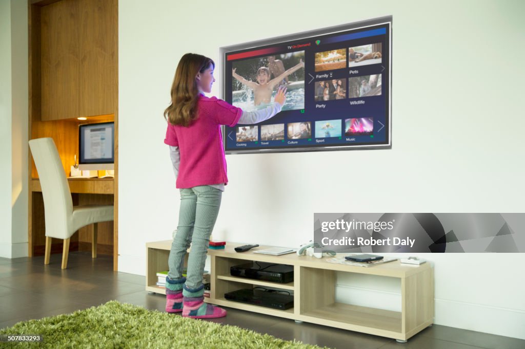 Garota usando televisão touch screen na sala de estar