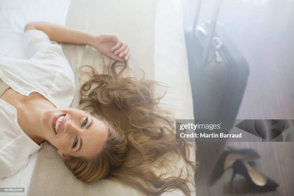 Businesswoman laying on bed in hotel room