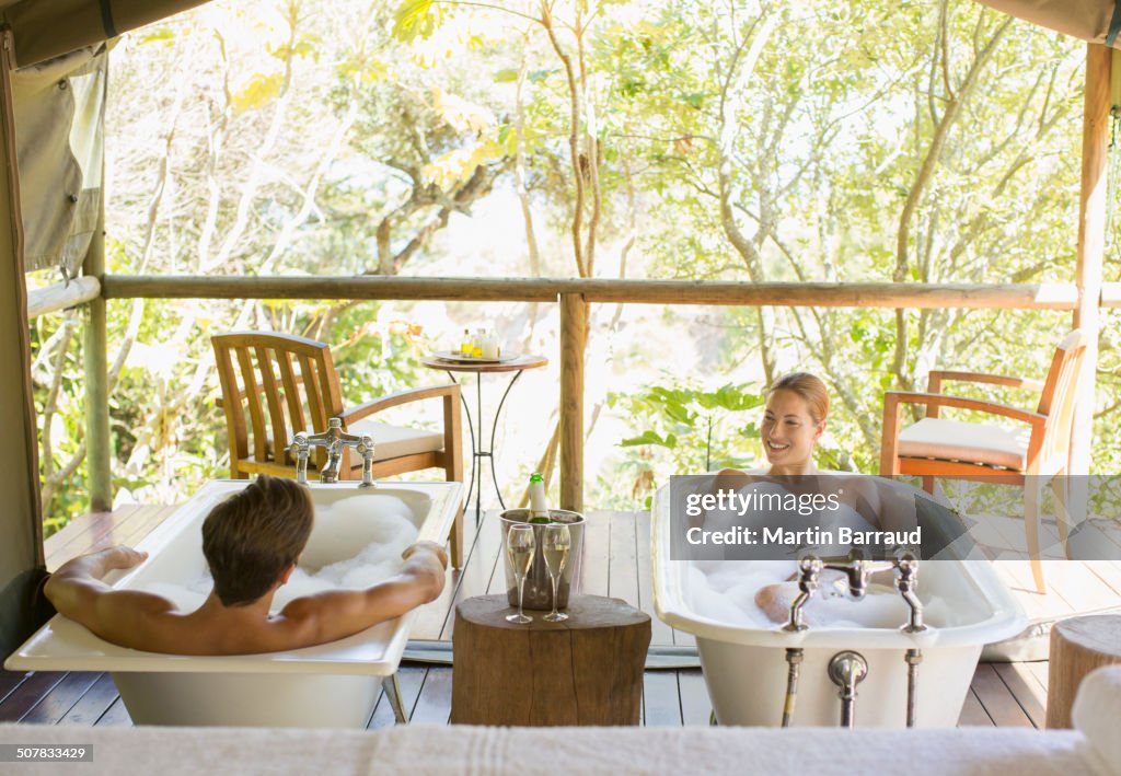 Couple in twin bathtubs in outdoor spa
