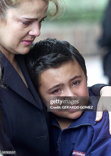 Una madre consuela a su hijo luego de depositar una ofrenda floral a la entrada del colegio Agustiniano Norte en Bogota, el 29 de abril de 2004. Un...