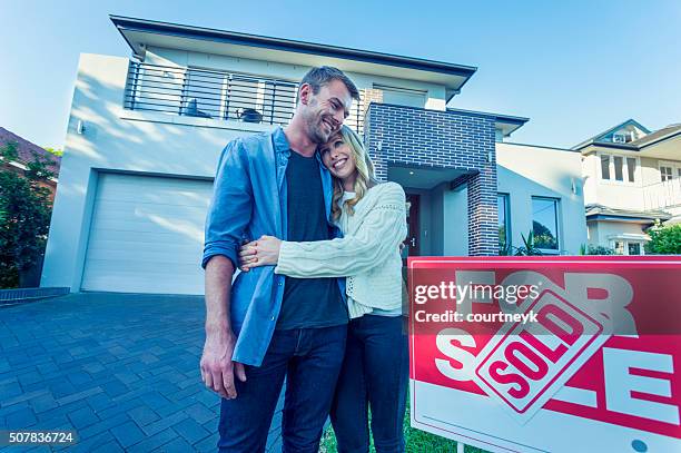 couple standing in front of a new home. - young couple shopping stock pictures, royalty-free photos & images