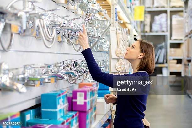 woman looking faucets at plumbing store - household fixture stock pictures, royalty-free photos & images