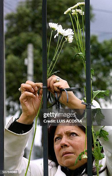Un familiar coloca una ofrenda de flores frente al colegio Agustiniano, en Bogota el 29 de abril de 2004. Un total de 22 ninos y un adulto muertos, y...