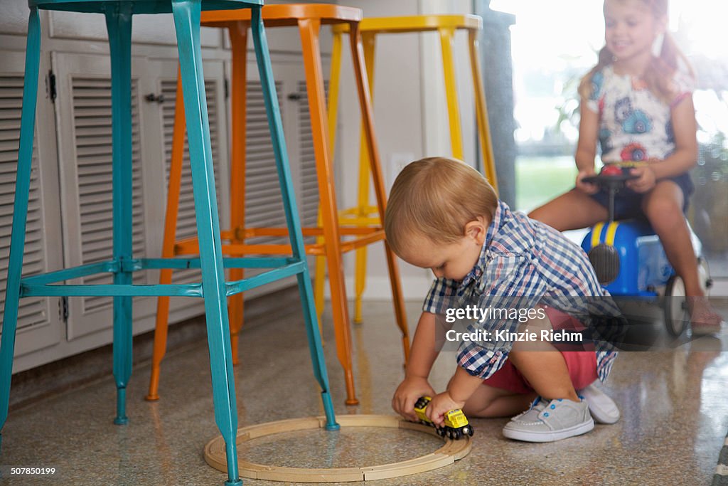 Male toddler and sister playing in kitchen