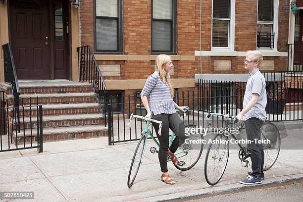 young couple with bicycles chatting on street - queens stad new york stock-fotos und bilder