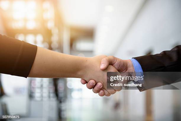 close up of businesswomen and businessman shaking hands in office - uomo donna per mano foto e immagini stock