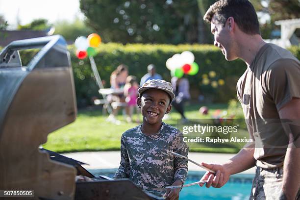 male soldier and boy barbecuing at homecoming party - homecoming stock pictures, royalty-free photos & images