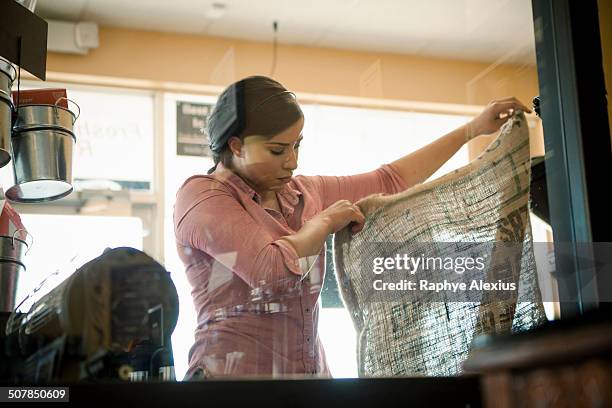 young woman holding up empty sack used for coffee roasting machine in cafe - monroe michigan - fotografias e filmes do acervo