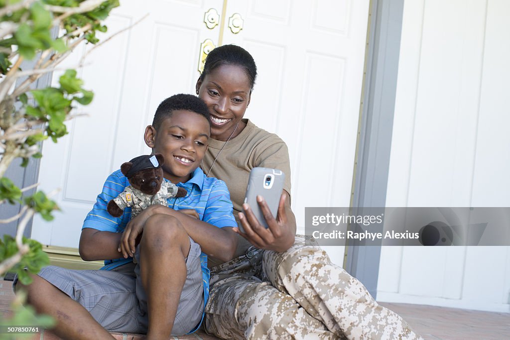 Female soldier taking selfie with son at front door on homecoming
