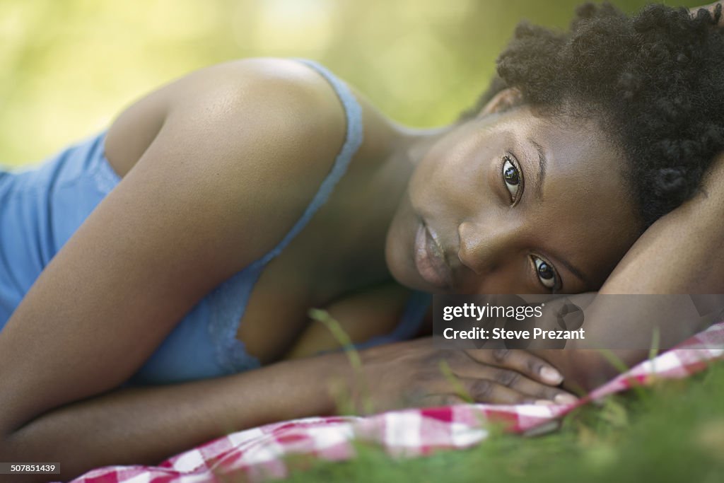 Portrait of young woman lying on side in park