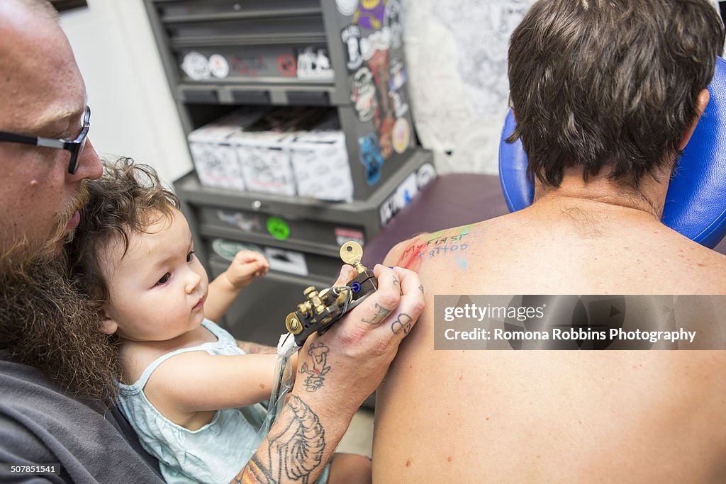 Tattoo artist showing toddler how to give a tattoo